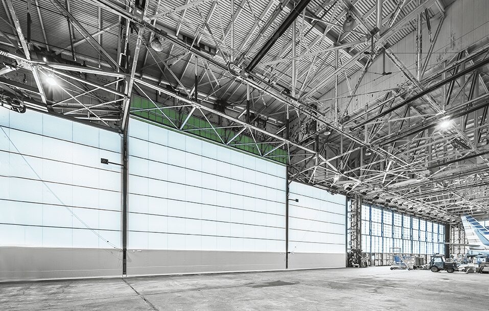 Interior of a large industrial warehouse with open garage doors.